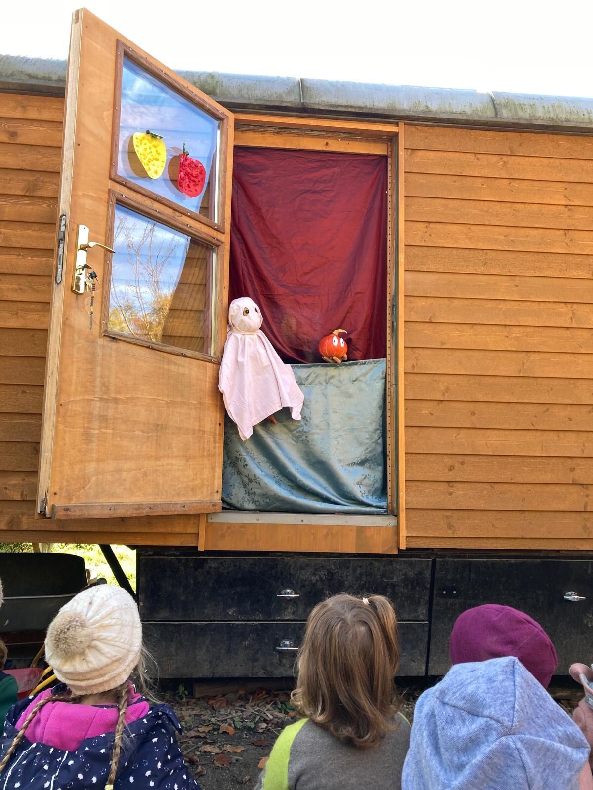 Kasperltheater am Bauwagenfenster, die Kinder schauen gebannt zu