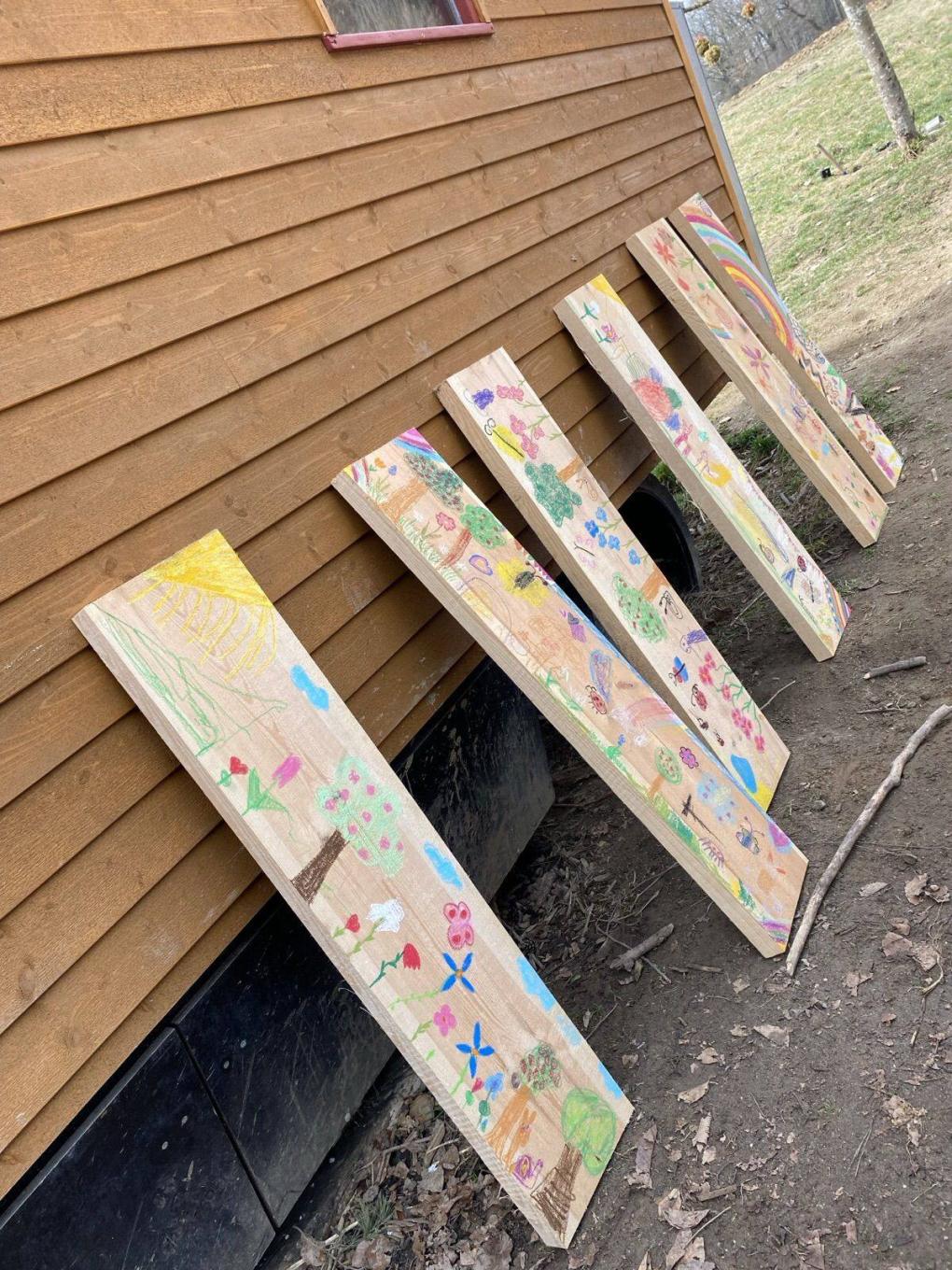 Von den Kindern bunt bemalte Holzbretter lehnen am Bauwagen