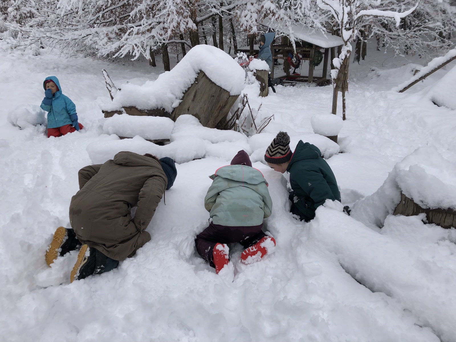 Kinder graben Höhlen in den tiefen Schnee am Bauwagenplatz